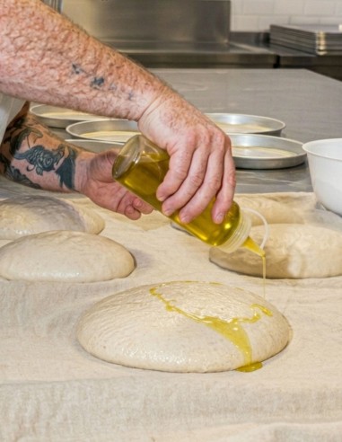 Biberón de plástico dosificando aceite sobre masa