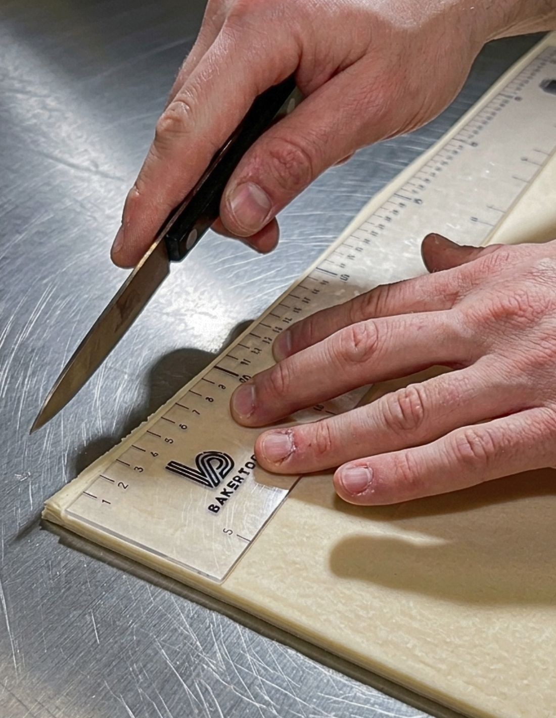 Corte de masa hojaldrada con cuchillo de puntilla y regla transparente